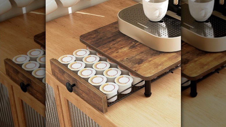 A wooden shelf with black legs and a coffee pod drawer on a counter.
