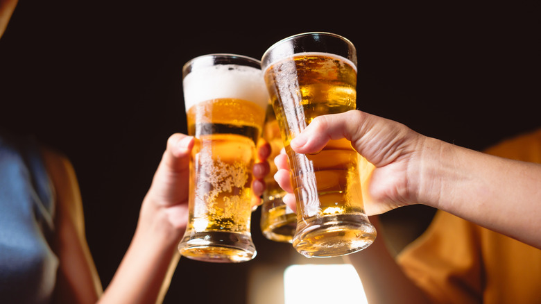 A group of people clink glasses of beer together
