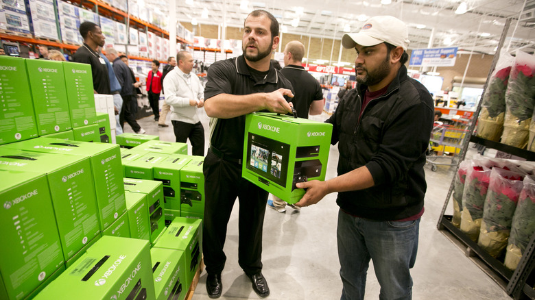 Man handing XBOX to customer in Costco