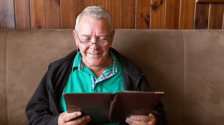 An older man looks at a restaurant menu