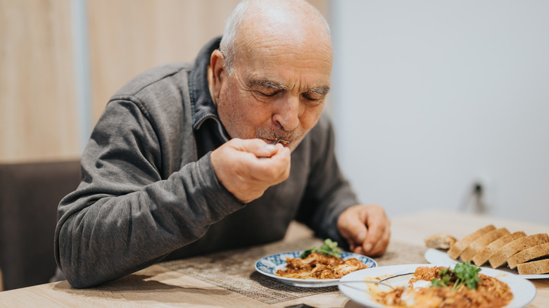 An older man eats a plate of food