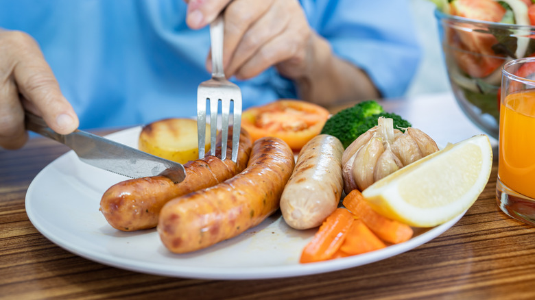 An older person eats a plate of food