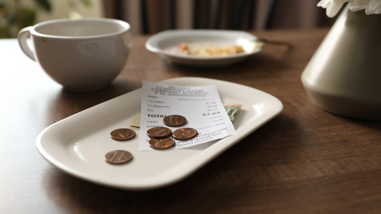 A tip plate, with a receipt, coins, and bills