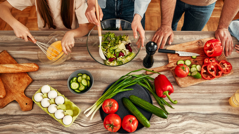 A family of three people work together prepping different dishes for their meal