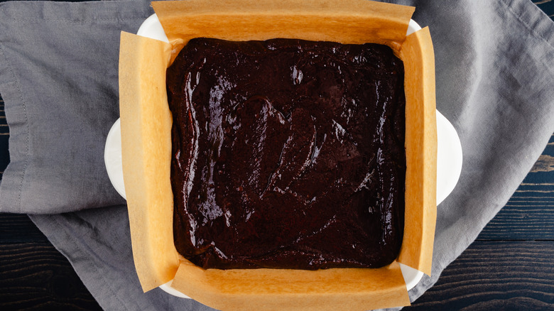 Brownie batter in a baking dish lined with parchment paper