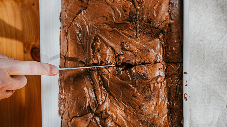 A person cutting a slab of brownies