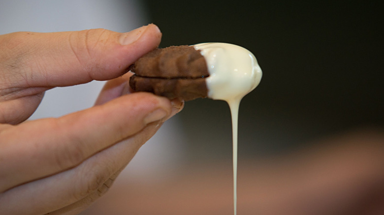 A person holding a cookie that is dipped in icing