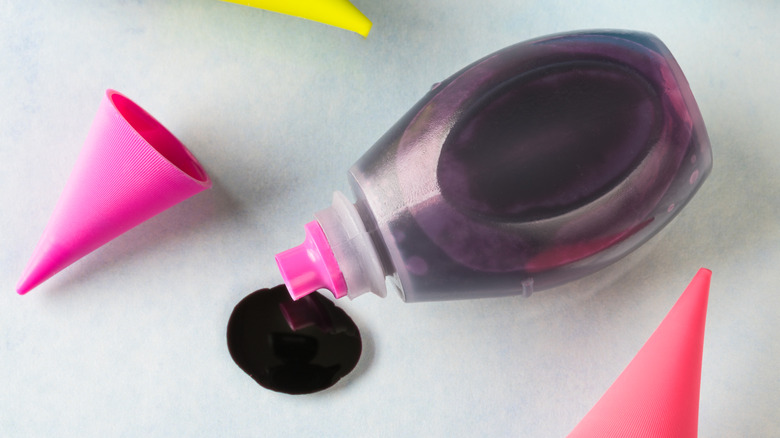 An open bottle of pink liquid food color on a white table