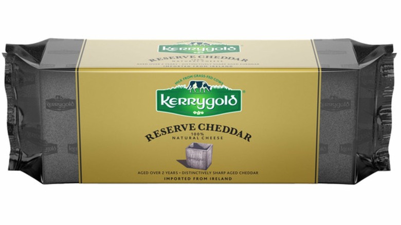 Wrapped block of Kerrygold Reserve Cheddar against white background.
