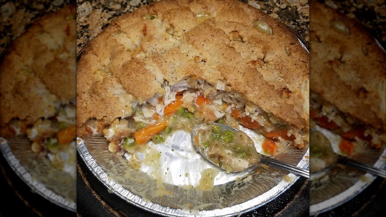 Costco chicken pot pie in a metal tray, with a large wedge taken out of it, to show the filling