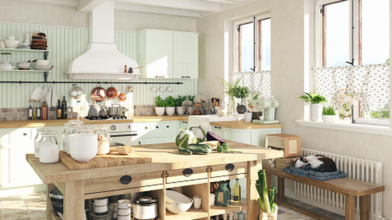 Bright kitchen with mint green walls, wood island, plants