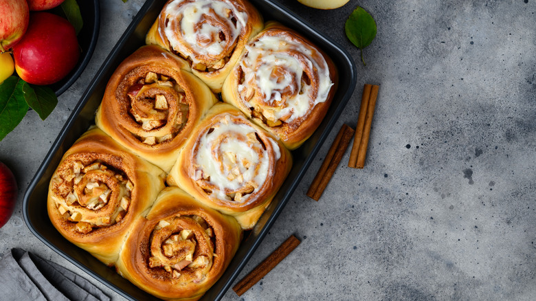 Freshly baked cinnamon rolls in a baking dish topped with frosting