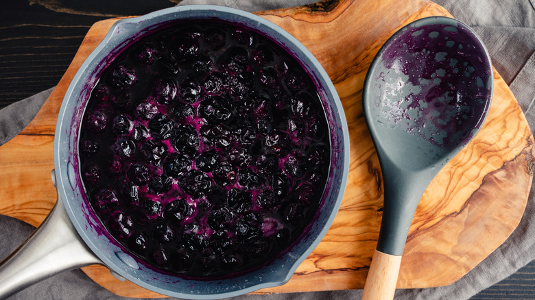 Blueberry compote in a saucepan with a spoon on the side