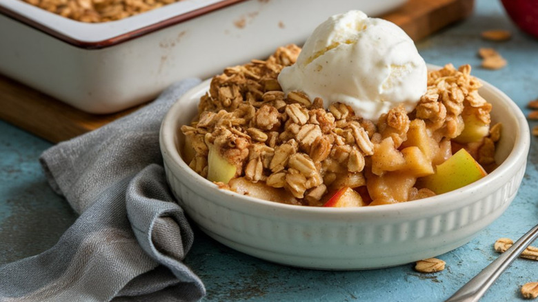 Apple crisp in a white plate topped with vanilla ice cream
