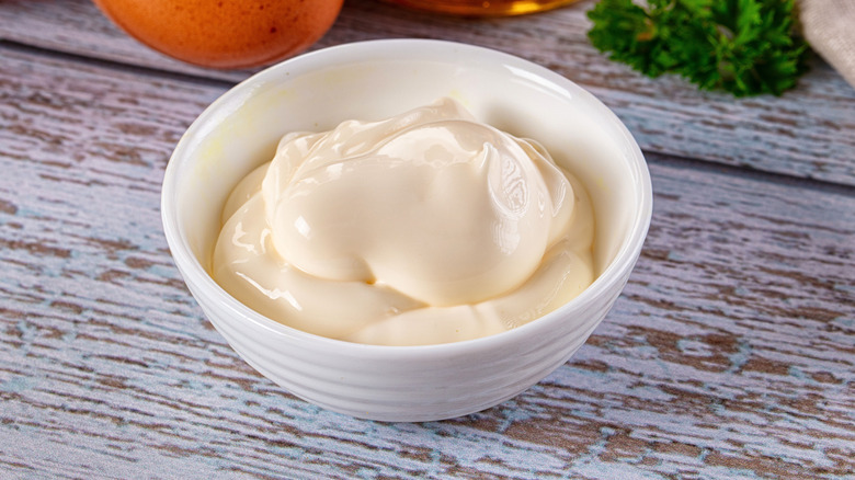 Mayonnaise in a white bowl on a wooden table