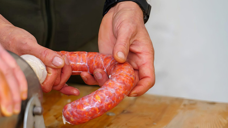 A person holding a sausage while it's getting stuffed