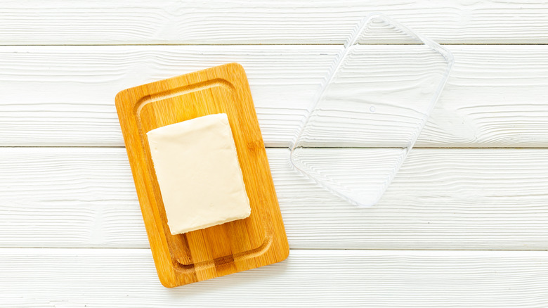 A block of butter on a butter dish, placed on a white table