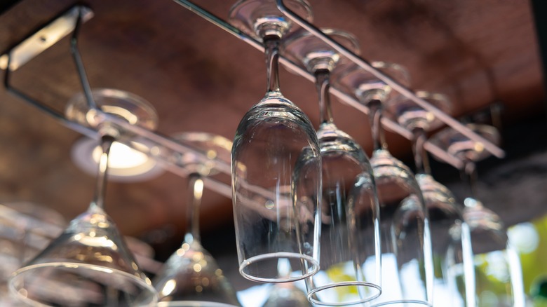 A row of champagne and cocktail glasses hang in a window