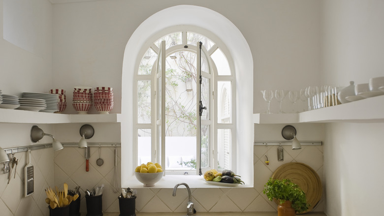 A view of an arched kitchen window, surrounded by open shelving
