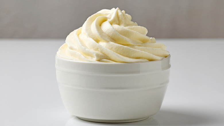 Whipped coconut cream in a white bowl placed on a white table