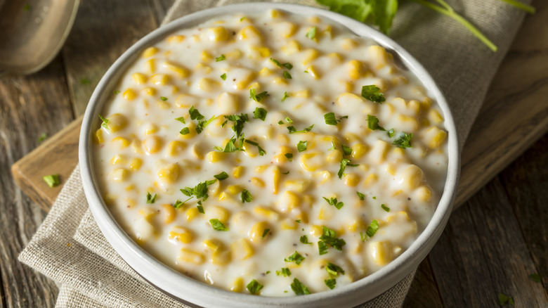 A bowl full of creamed corn on a wooden table