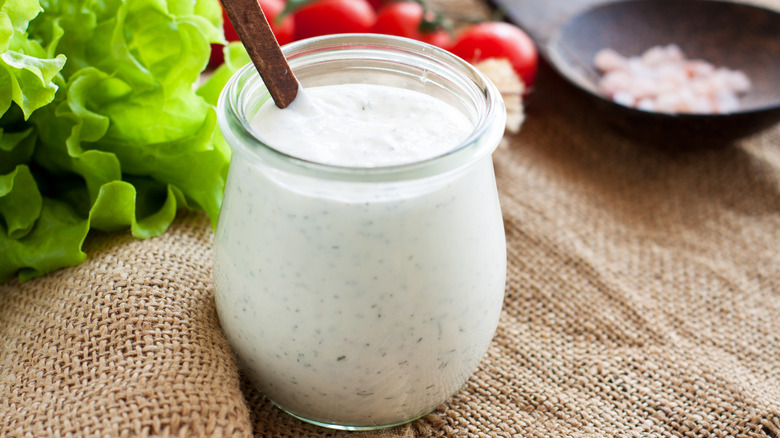 A jar full of creamy salad dressing on a table