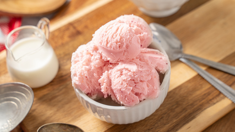 Strawberry ice cream in a bowl with placed on a wooden board