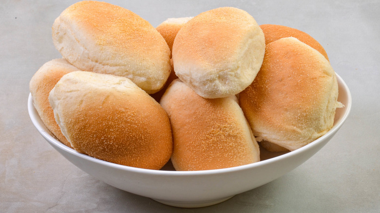 A bowl full of bread rolls placed on a gray table