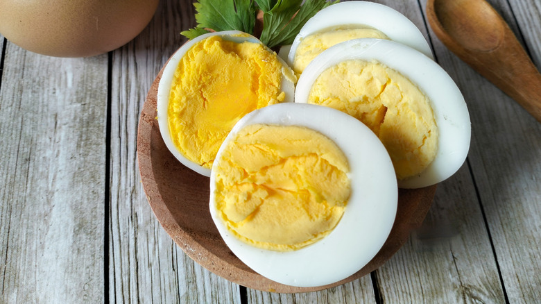 Boiled eggs on a wooden plate placed on a wooden table