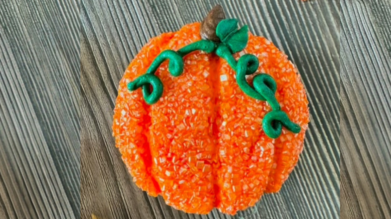 A cupcake decorated to look like a pumpkin on a table