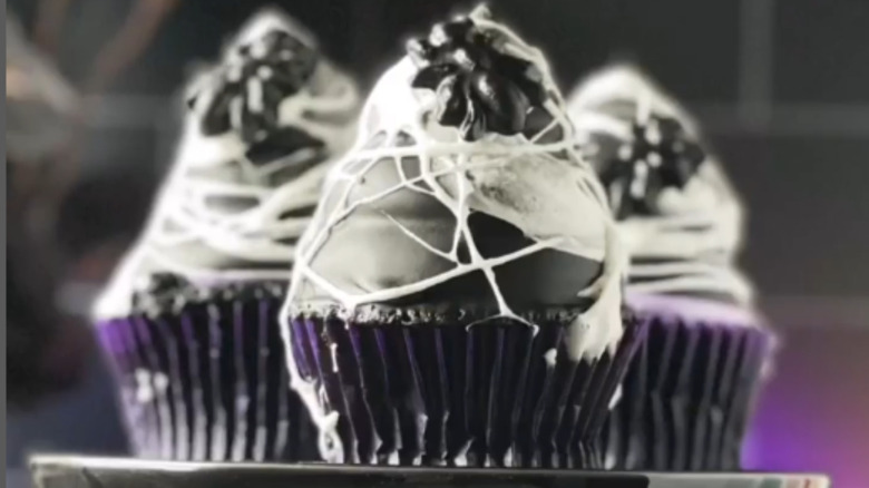 three Spider Web Cupcakes with melted marshmallow webbing on a tray