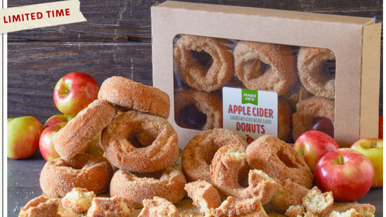 Trader Joe's Apple Cider Donuts toppled on eachother next to a propped up package version of the product