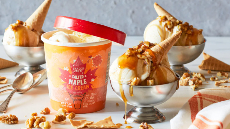 A pint of Salted Maple Ice Cream surrounded by bowls of ice cream with cones and maple syrup