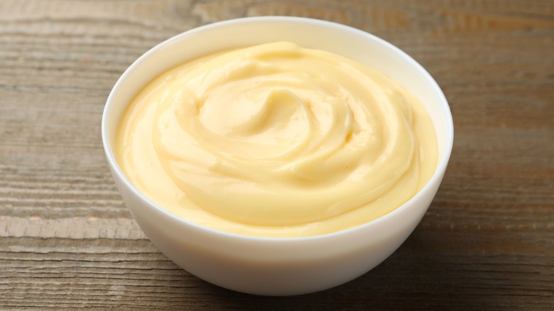 Cream-colored pudding in a white bowl on wooden surface
