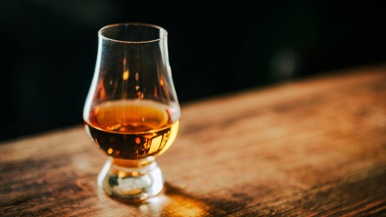 A glass of whiskey on a wooden table
