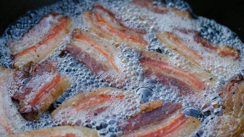 Bacon strips in a frying pan with a lot of bacon grease