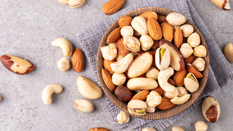 Different types of nuts in a wooden bowl placed on a table