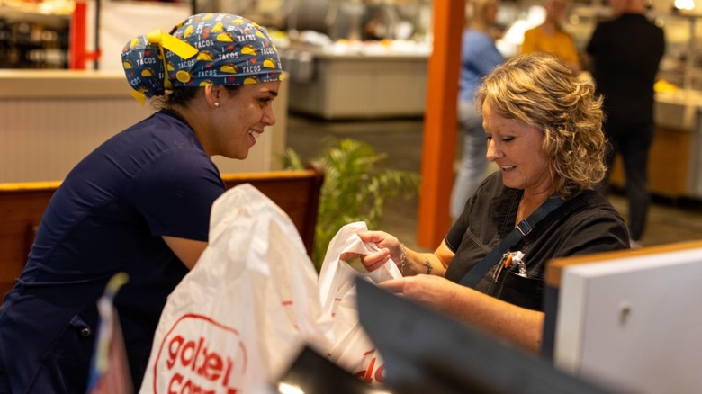 A Golden Corral employee handing a take-out order to a customer