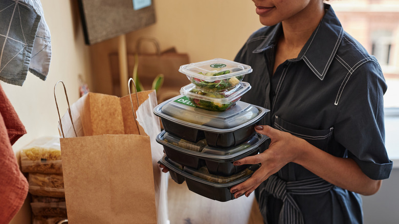 A woman holding stack of to-go containers