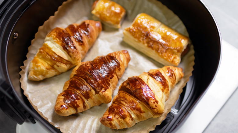 Cooked croissants and other pastries in lined air fryer basket