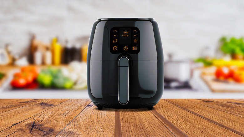 Sleek black air fryer sitting on wooden countertop