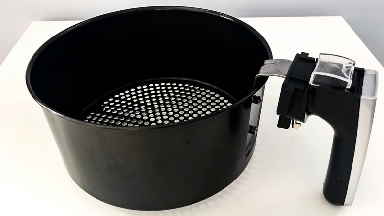 Clean black air fryer basket sitting on white table