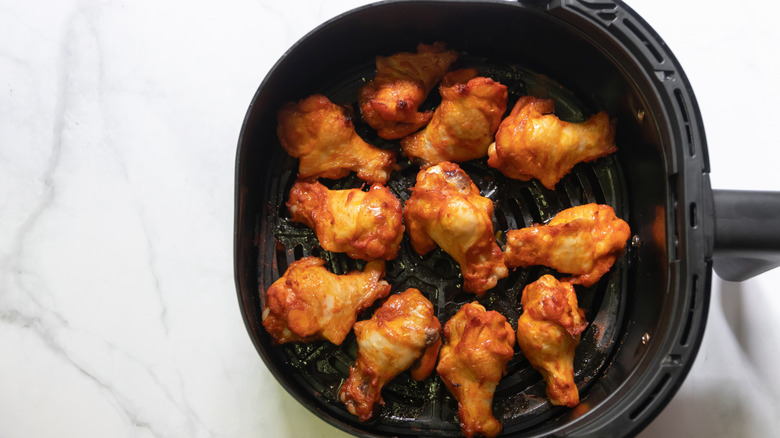 Cooked marinated chicken wings in air fryer basket