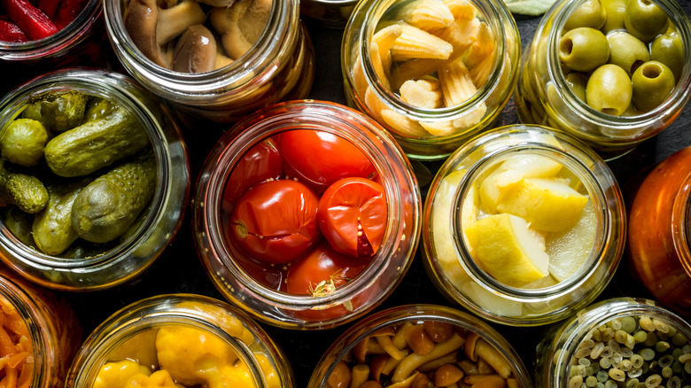 Overhead view of open jars filled with different pickled vegetables