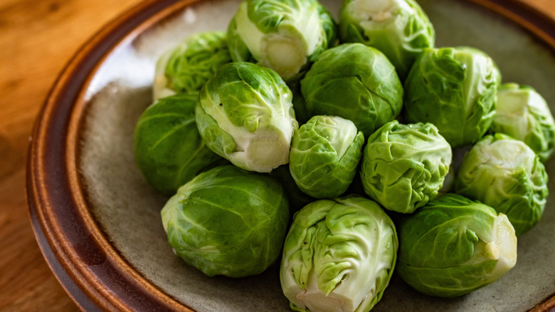 A bowl of raw Brussels sprouts on a wooden table