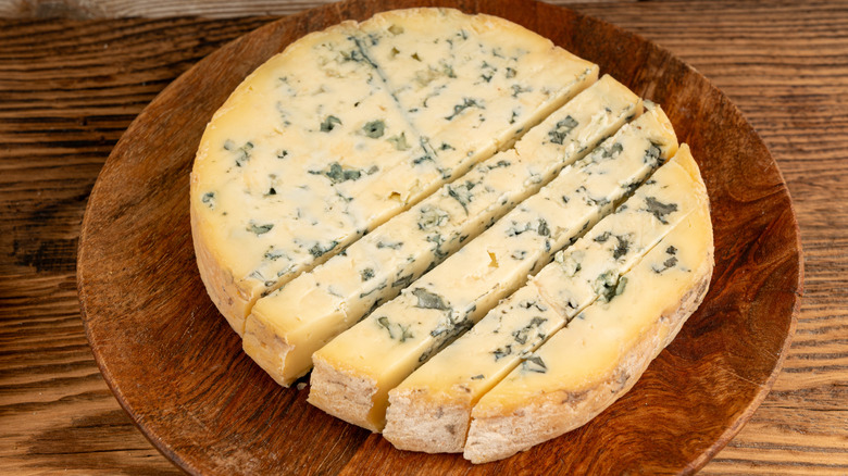 A sliced block of aged cheese on a wooden table