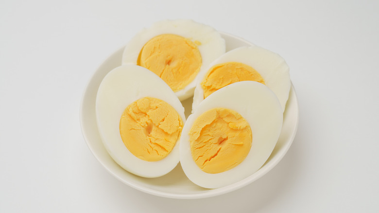 Hard-boiled egg halves in a white bowl placed on a white table