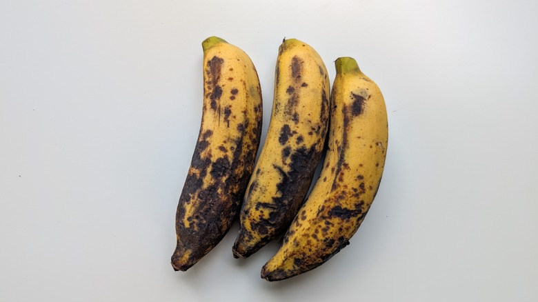 Three overripe bananas on a white table