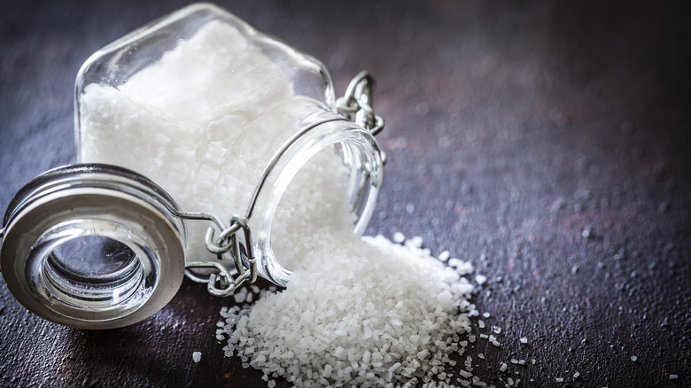 Salt in bottle spilled on dark table