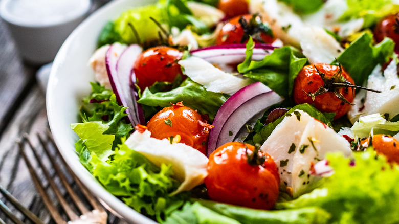 A salad in a bowl with tomatoes, onions, and cheese